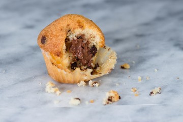 Leftover unfinished muffin with cocoa filling and chocolate chips on marble surface