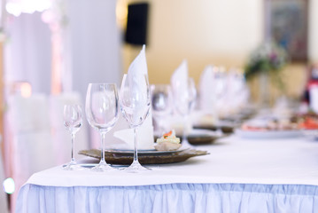 Sparkling glassware stands on long table prepared for wedding dinner. Champagne glasses on the celebration table.