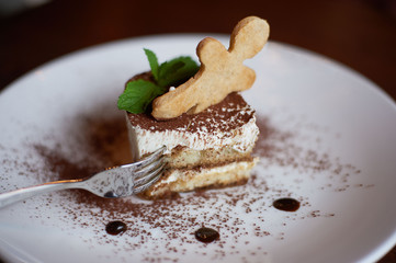 Tiramisu with cake and peppermint leaves on the plate with fork
