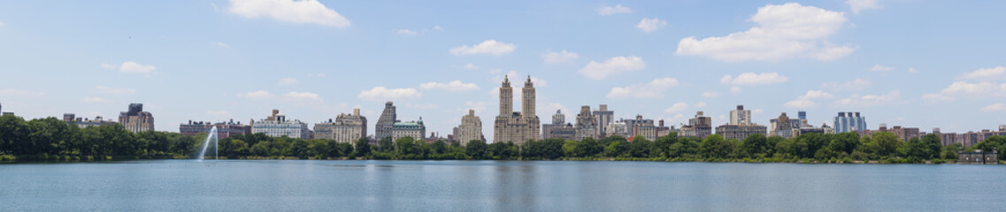 Fototapeta na wymiar Central Park West skyline and the Jacqueline Kennedy Reservoir in New York City with apartment skyscrapers over lake with fountain in midtown Manhattan and lake reflection 
