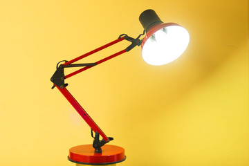 red metallic desk lamp on yellow background