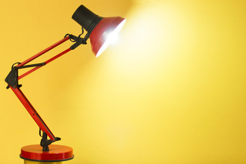 a red metallic desk lamp on a yellow background