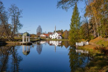 Fototapeta na wymiar Rich old estate with a pond, rotunda and decorative pier. Palmse, Estonia. Autumn sunny day.