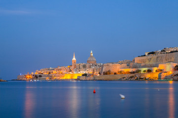 Summer night view of Valetta profile over sea. Long exposure. Illuminated architecture.