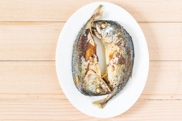 Fried two short mackerel fishes on wooden floor