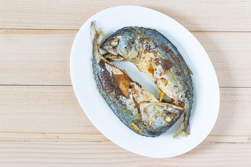 Fried two short mackerel fishes on wooden floor