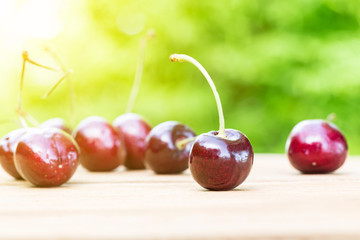 Cherries on wooden table with green bokeh background