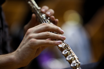 Fototapeta premium Detail of a musician flute in his hands closeup in dark colors