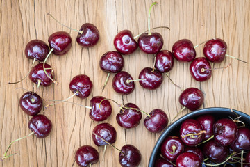Cherry with black bowl on wooden table taken in top view