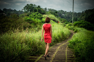 Young sexy woman in red dress in the tropical landscape of Bali island, Indonesia. Woman having summer vacation and enjoy paradise.