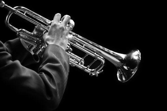 Hands of a musician playing on a trumpet closeup in black and white tones on a black background