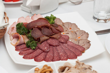 Dish with delicious sliced salami, slices of ham, sausage, beef tongue, parsley. Meat dish with selection.