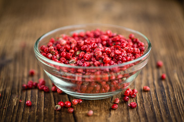 Pink Peppercorns on wooden background; selective focus
