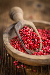 Pink Peppercorns on wooden background; selective focus