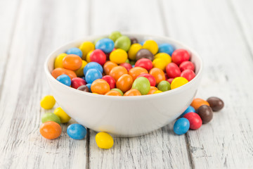 Portion of Cocolate coated Peanuts on wooden background (selective focus)