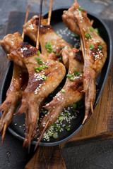 Metal plate with grilled chicken wings on wooden skewers, close-up, selective focus