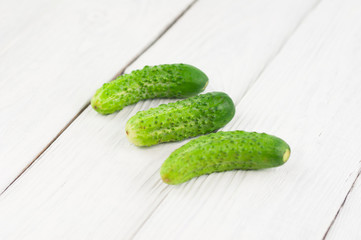 Three green ripe cucumbers on old white planks