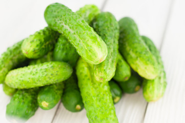 Heap of green fresh cucumbers on white rustic background