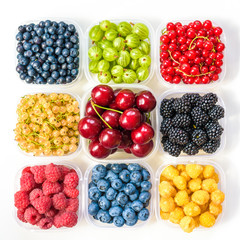 Collage of different fruits and berries isolated on white. Blueberries, cherries, blackberries, grapes, strawberries, currants. Collection of fruits and berries in a bowl. Top view