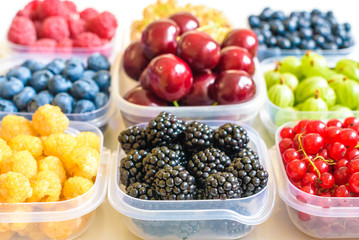 Collage of different fruits and berries isolated on white. Blueberries, cherries, blackberries, grapes, strawberries, currants. Collection of fruits and berries in a bowl. Top view