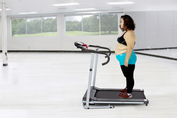 Fototapeta premium Fat woman exercising with a treadmill