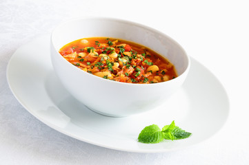 soup of butter beans, smoked ham, and tomato decorated with mint