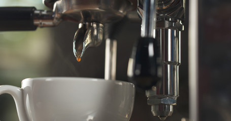 last drop coffee pour from professional coffee machine into cappuccino cup