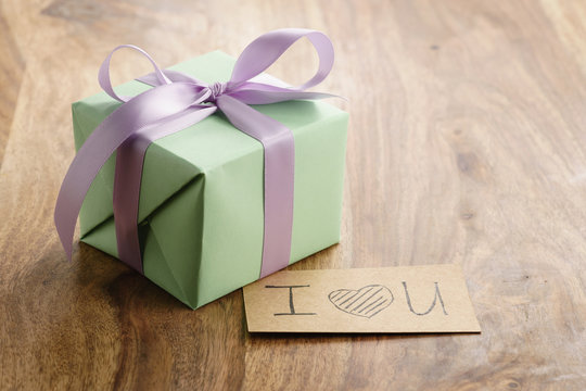 green gift box with purple bow wood background with i love you greeting card