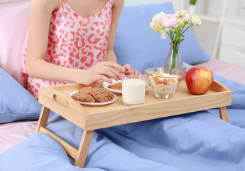 Young woman having breakfast in bed at home