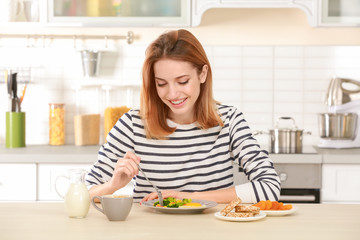 Obraz na płótnie Canvas Young pretty woman having delicious breakfast in light kitchen