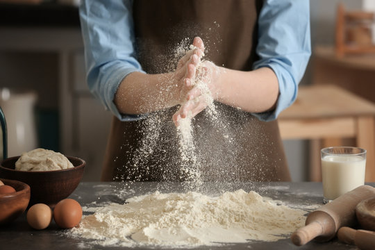 Female chef with flour and ingredients for dough on table in kitchen