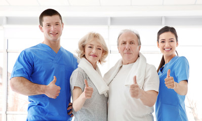 Physiotherapists with elderly patients in modern clinic
