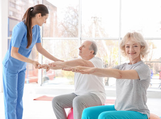 Obraz premium Fizjoterapeuta pracujący z pacjentami w podeszłym wieku w nowoczesnej klinice