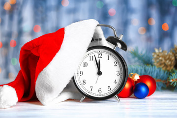 Retro alarm clock with Santa hat and decorations on wooden table. Christmas countdown concept