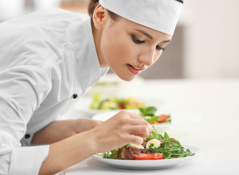 Young female chef cooking in kitchen