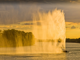 Dark clouds and strong wind create water curtain from artificial geysir against sunset light on Ada lake in Belgrade, Serbia