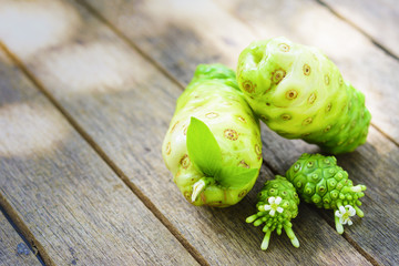 Noni fruit and blossom on old wooden table.Fruit for health and detox