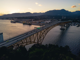 Obraz premium Aerial shot of bridge over river while sunset behind mountains
