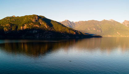 Aerial shot of kayaker on lake with mountains while  sunset