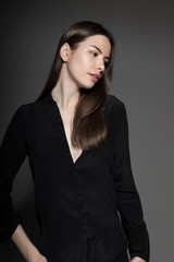 European attractive sexy fashion model with natural brunette hair, posing in studio, wearing black shirt, dark background, beauty photo shot, retouched image