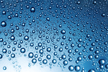 Naklejka na ściany i meble Water drops on rough surface, blue background 