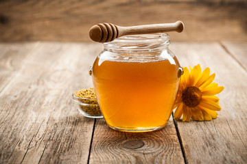Honey in glass jar on wooden background