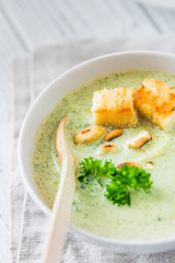 Green healthy cream soup with  broccoli, crackers, cashew, parsley. Close up