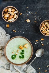 Green healthy cream soup with  broccoli, crackers, cashew, parsley. Top view
