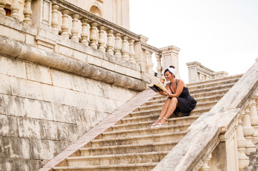 Fototapeta na wymiar Woman reading while sitting on a old town stairs