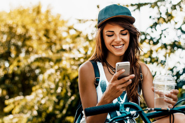 City lifestyle stylish hipster girl with bike using a smartphone