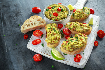 Homemade Guacamole toast with chili pepper, parsley on white wooden board