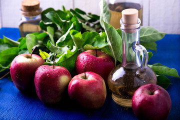 Apple cider vinegar. Three glass bottle on blue background. Red apples.