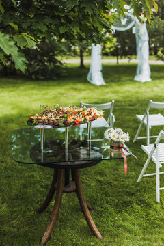 Catering for wedding party. Plenty of mixed various kinds of sliced fruit, vegetables,  cheese, chocolate sweets on big tray on table outdoors. Table decorated with vase full of white daisies flowers.