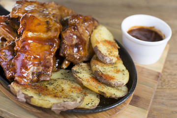 Delicious barbecued ribs seasoned with a spicy basting sauce and served with chopped potato on a...